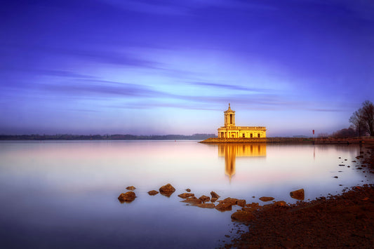 Fine art photograph of Normanton Church at blue hour on Rutland Water, with golden reflections on calm water under a deep twilight sky